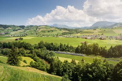 Der RegioExpress Kambly Zug schlängelt sich weit unten durch die schöne Sommerlandschaft.