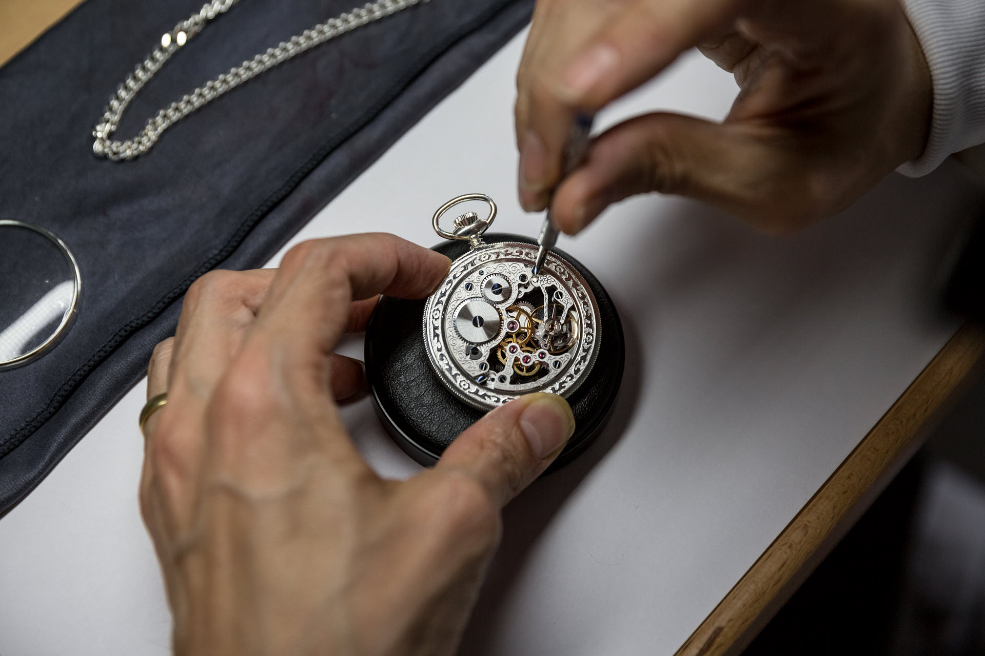 Zwei Hände die filigrane Arbeiten an einer Taschenuhr ausführen
