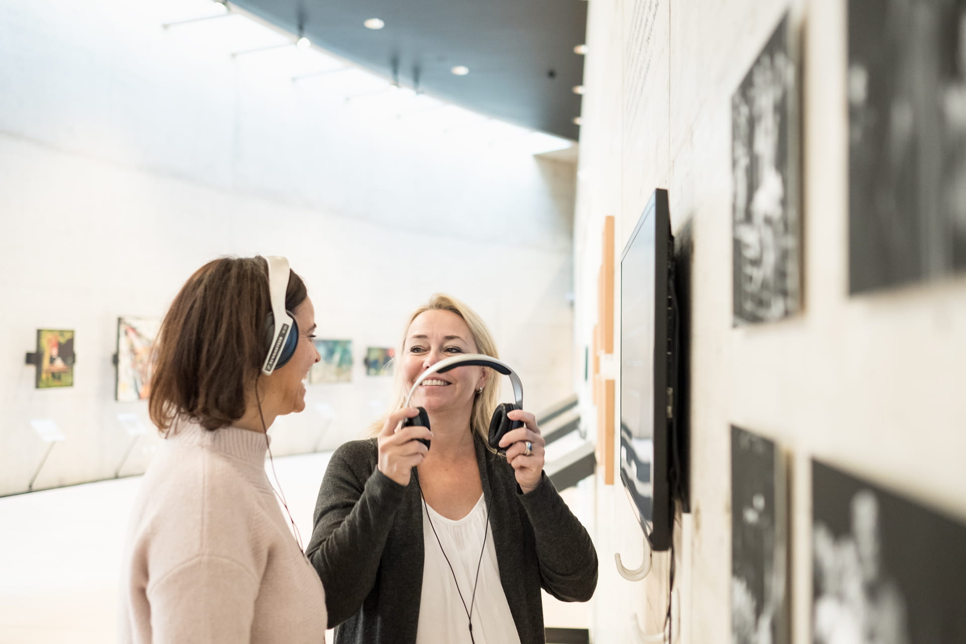 Zwei Freundinnen informieren sich über Kopfhörer über die Ausstellung im Museum.