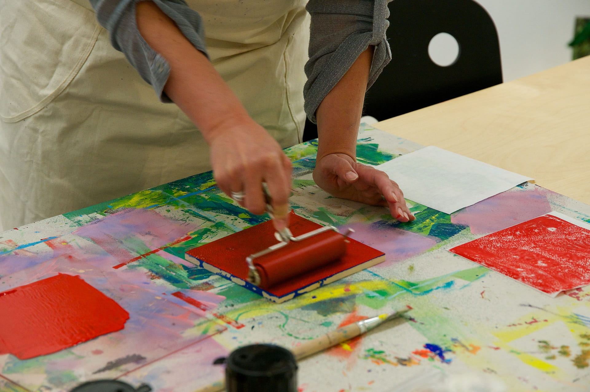 Eine Teilnehmerin des Workshops trägt Farbe auf das Drucknegativ auf.