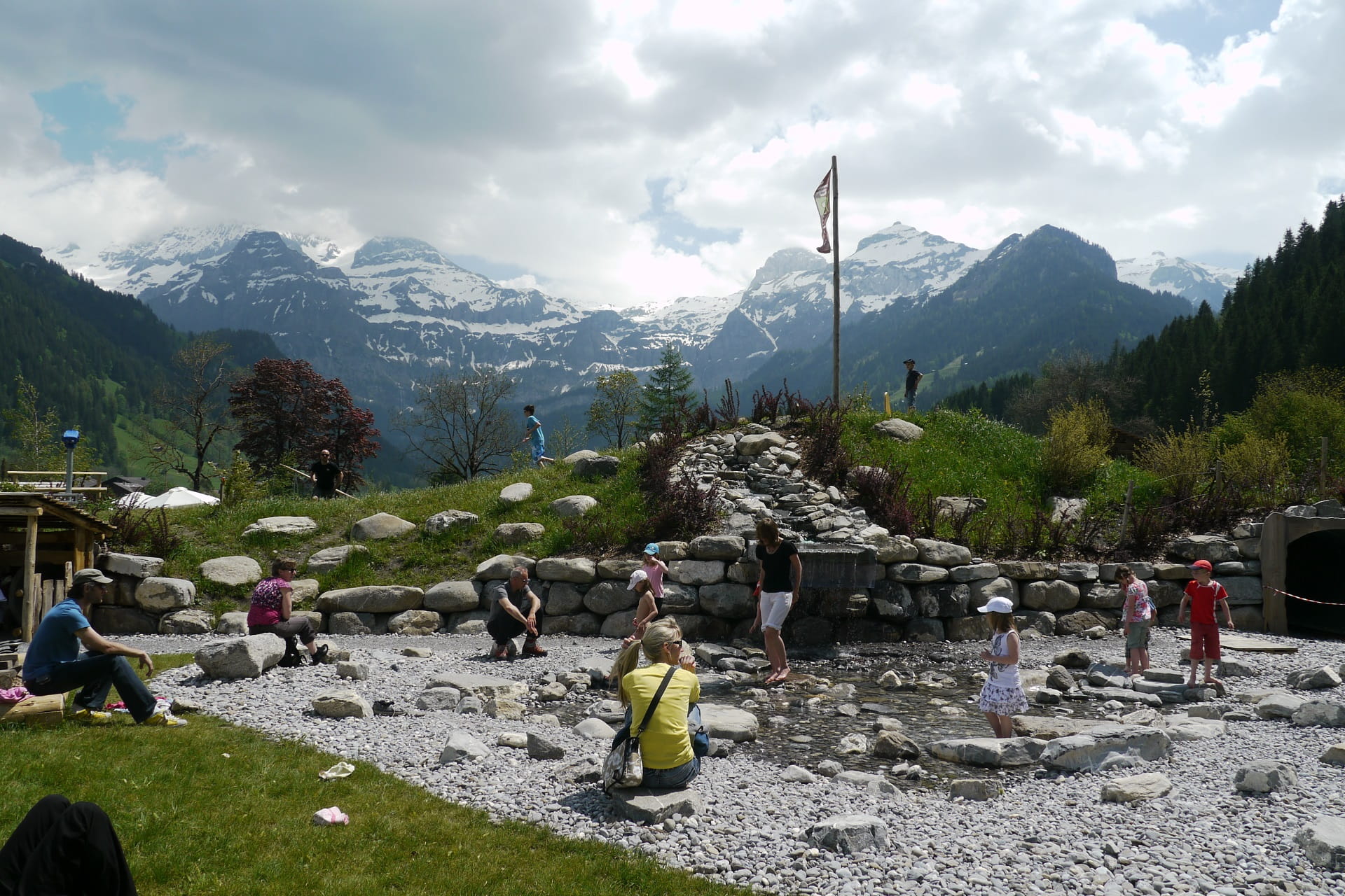 Kinder spielen am künstlichen Bächlein auf dem AlpKultur Spielplatz