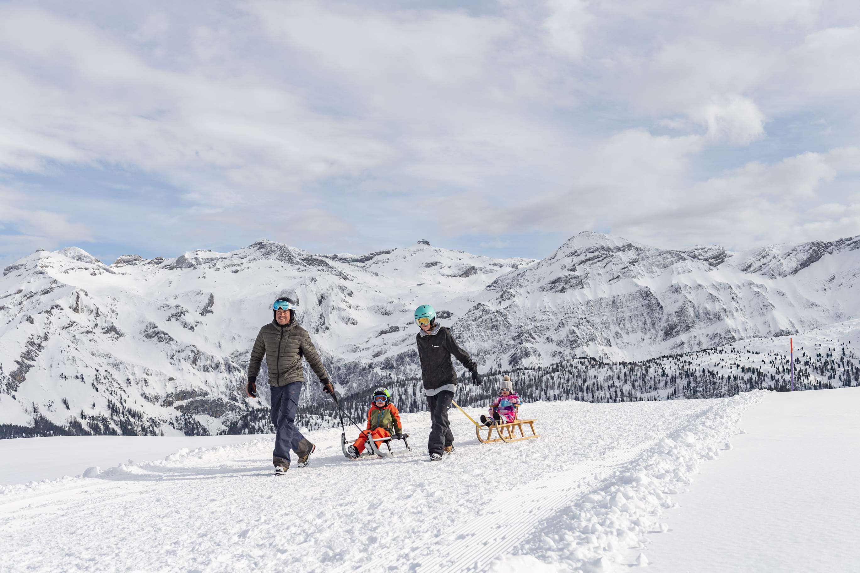 Lenk Betelberg Winter Mutter und Vater ziehen zwei Kinder auf Schlitten hinter sich her