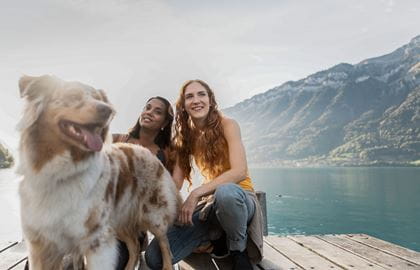 Two women with a dog on the shore of Lake Brienz