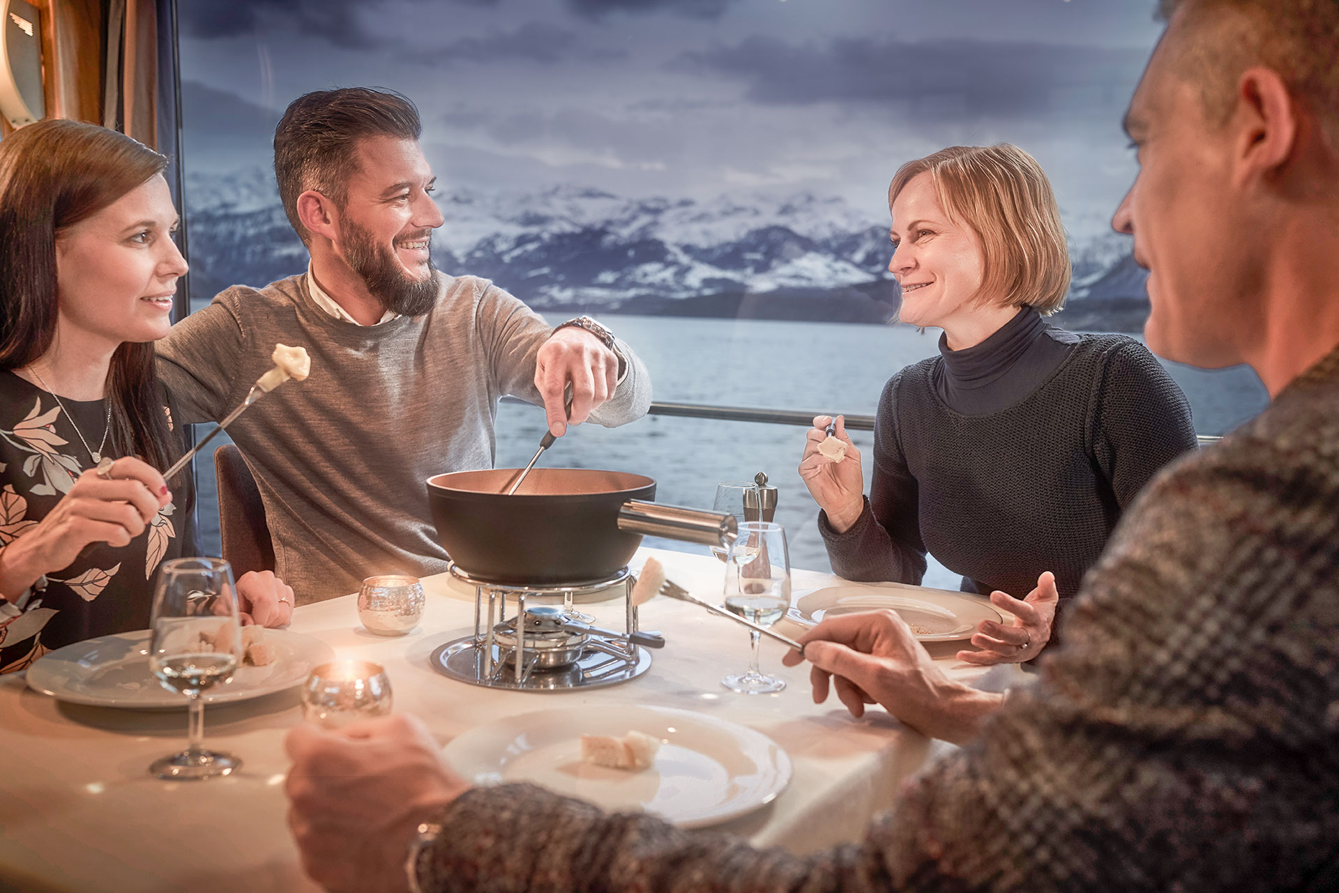 Zwei Paare an einem Tisch auf dem Schiff essen Käse-Fondue