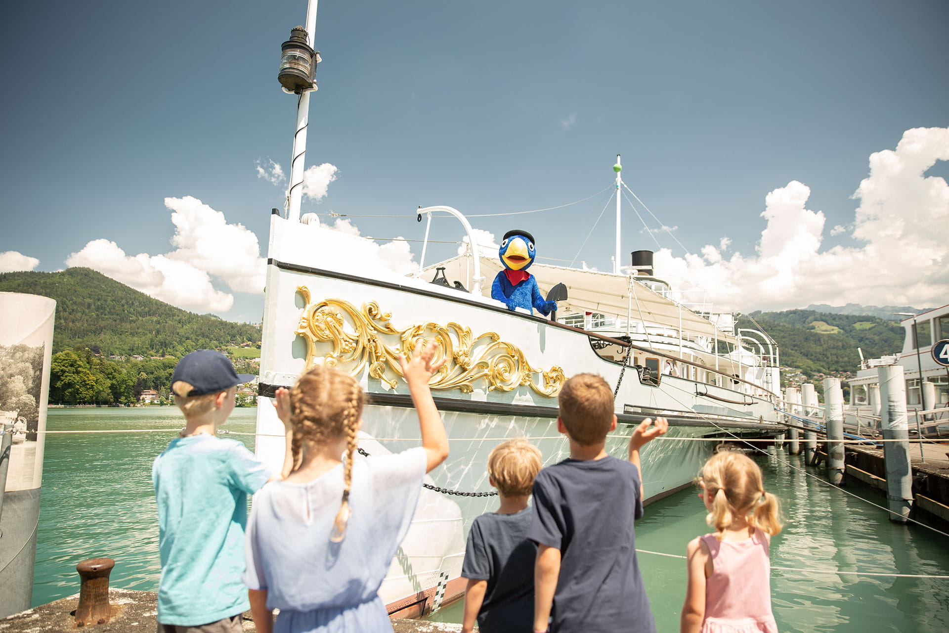Globi on the paddle steamer, waving to children
